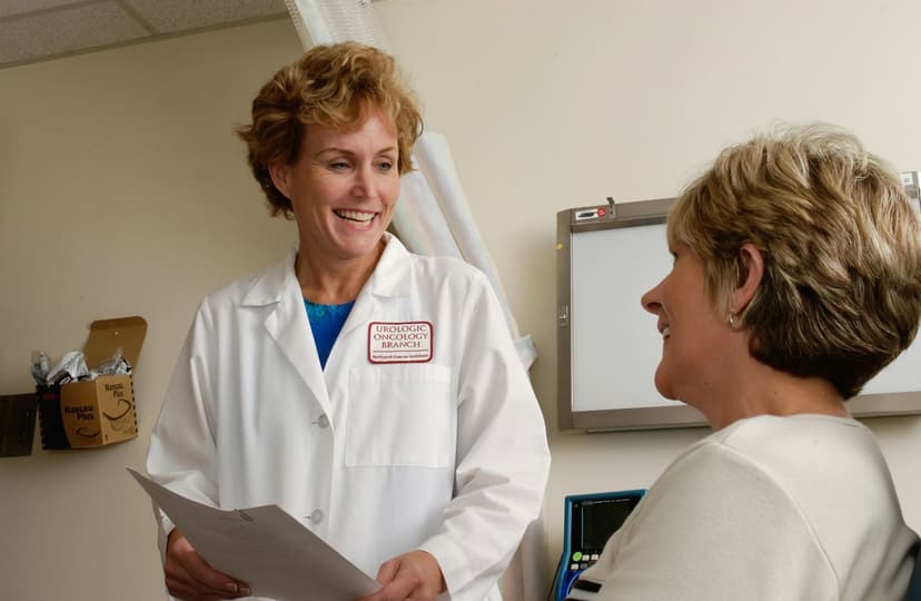 A doctor smiles while talking with a patient in an exam room.